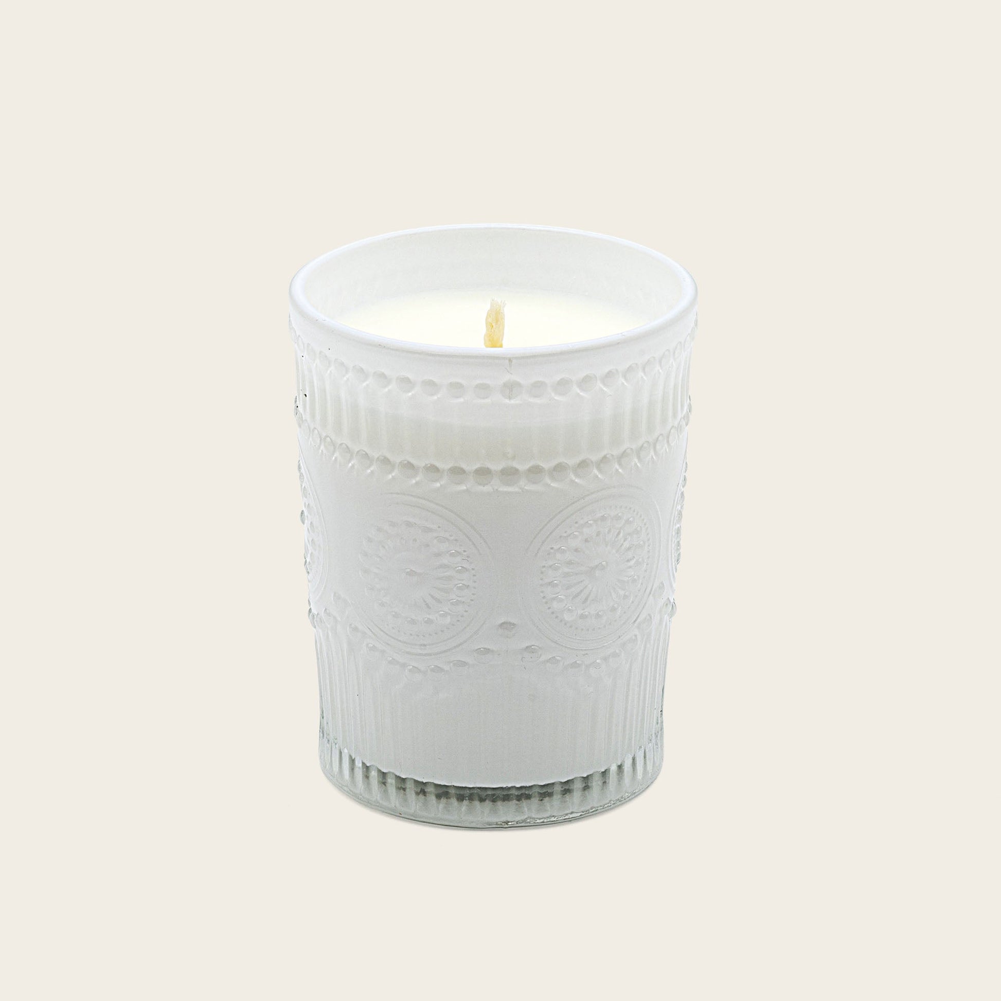 White embossed glass scented candle, lit flame