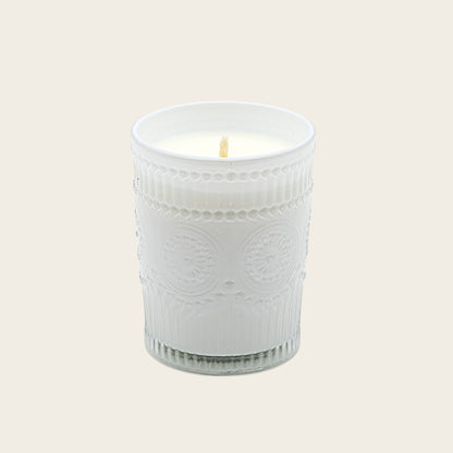 White embossed glass scented candle, lit flame