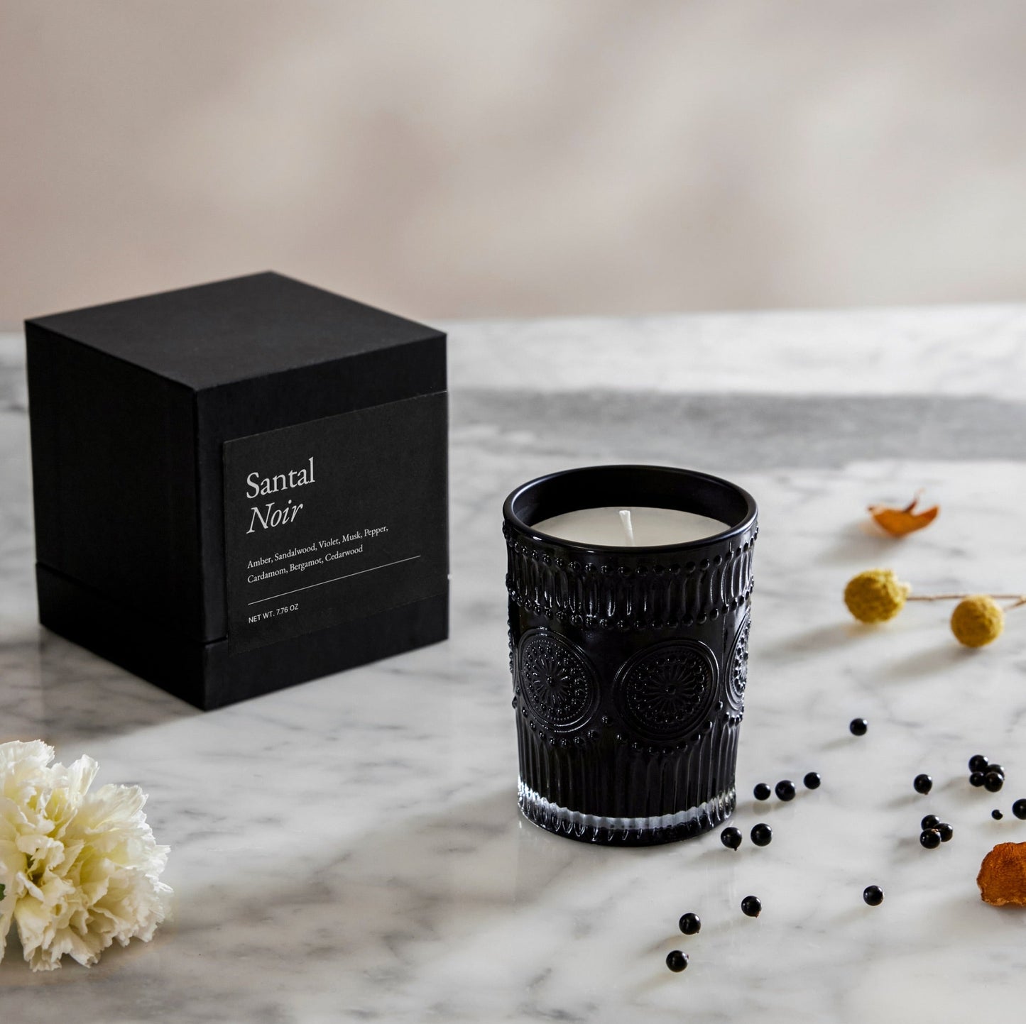 Santal Noir gift box next to dark ribbed glass candle with white wax and steady wick
