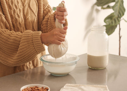 Nut milk bag being filled, off-white mesh pouch with rope drawstring