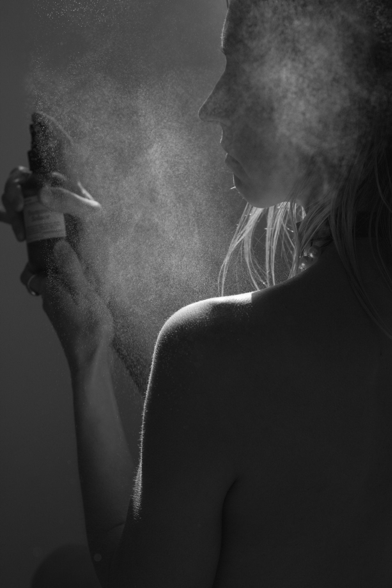 Person misting skin with facial toner spray bottle