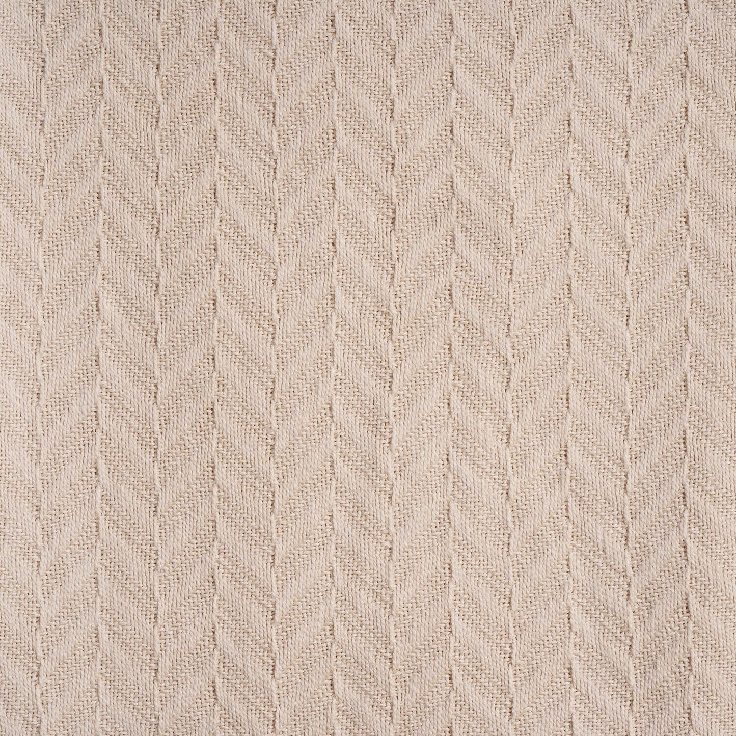 Herringbone knit cotton blanket close-up, ivory chevron pattern on textured fabric