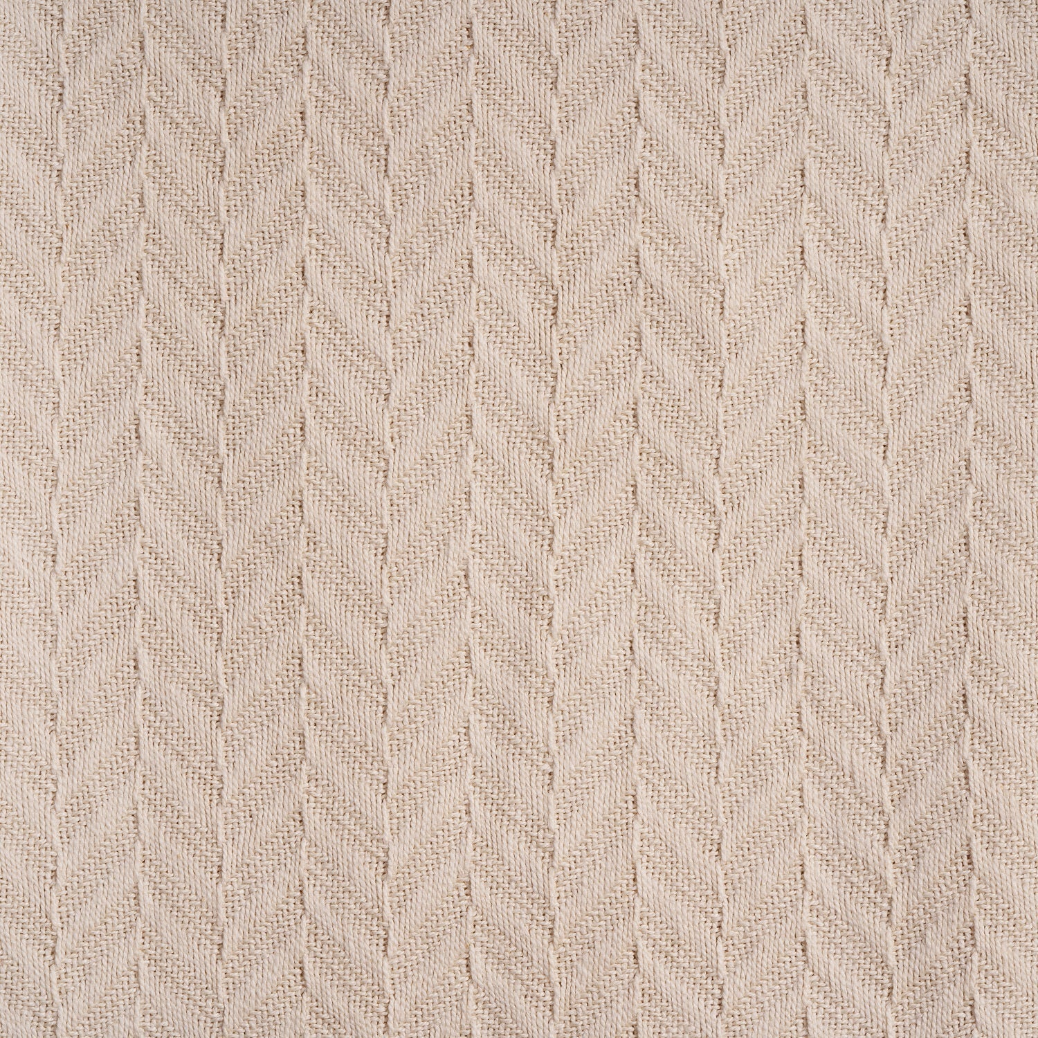 Herringbone knit cotton blanket close-up, ivory chevron pattern on textured fabric