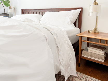 Organic percale bed sheets set, white fitted sheet and pillowcases on bed