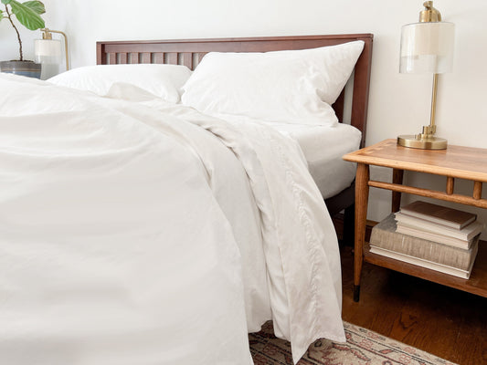 Organic percale bed sheets set, white fitted sheet and pillowcases on bed