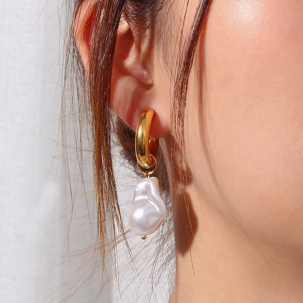 Gold-tone hoop earrings with white water-drop synthetic pearl drops, side view
