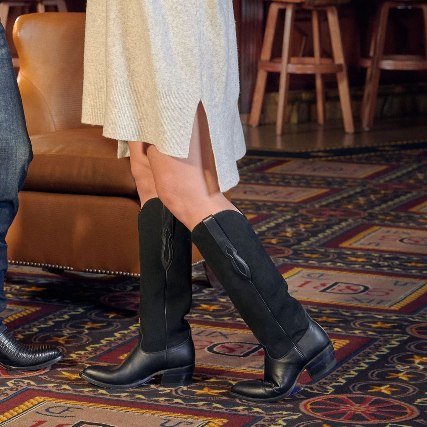 Black knee-high cowboy boots worn with a light skirt