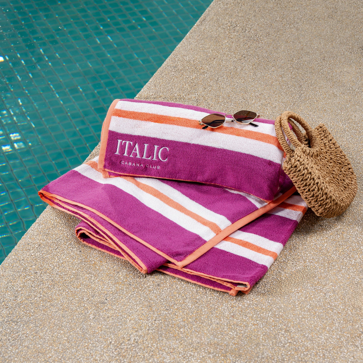 Pink and orange striped cotton beach towel with 'ITALIC' text on folded set