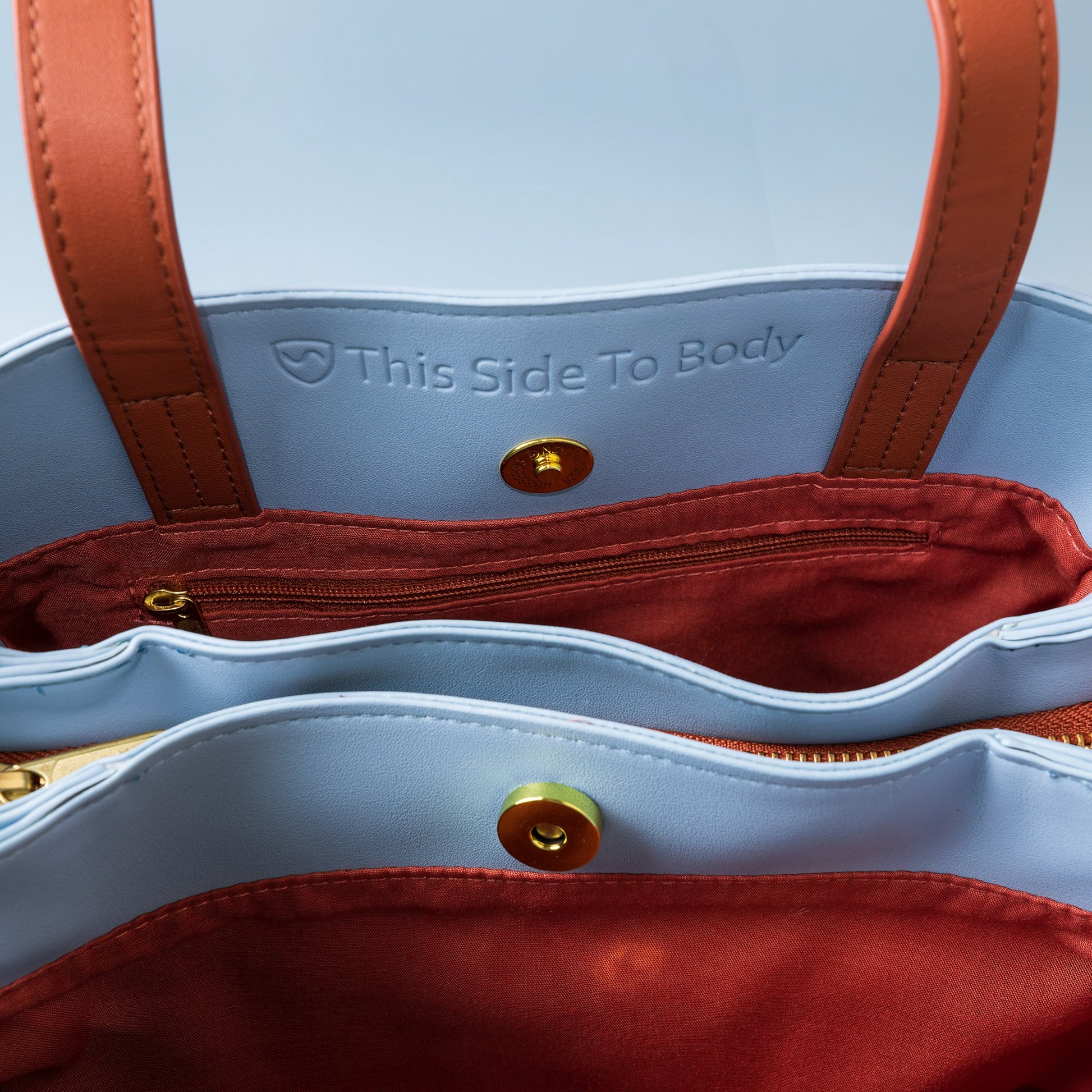 SYB purse interior close-up with brown straps and text 'This Side To Body'