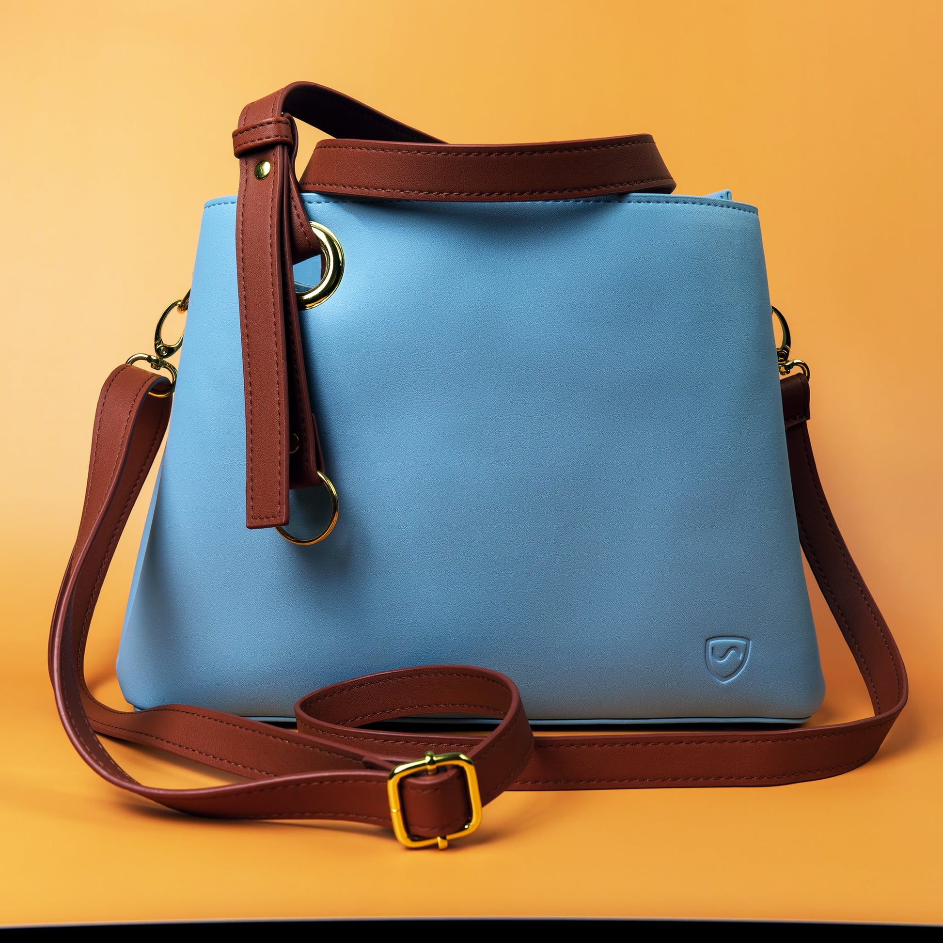 SYB blue purse with brown shoulder strap, gold hardware, and front logo