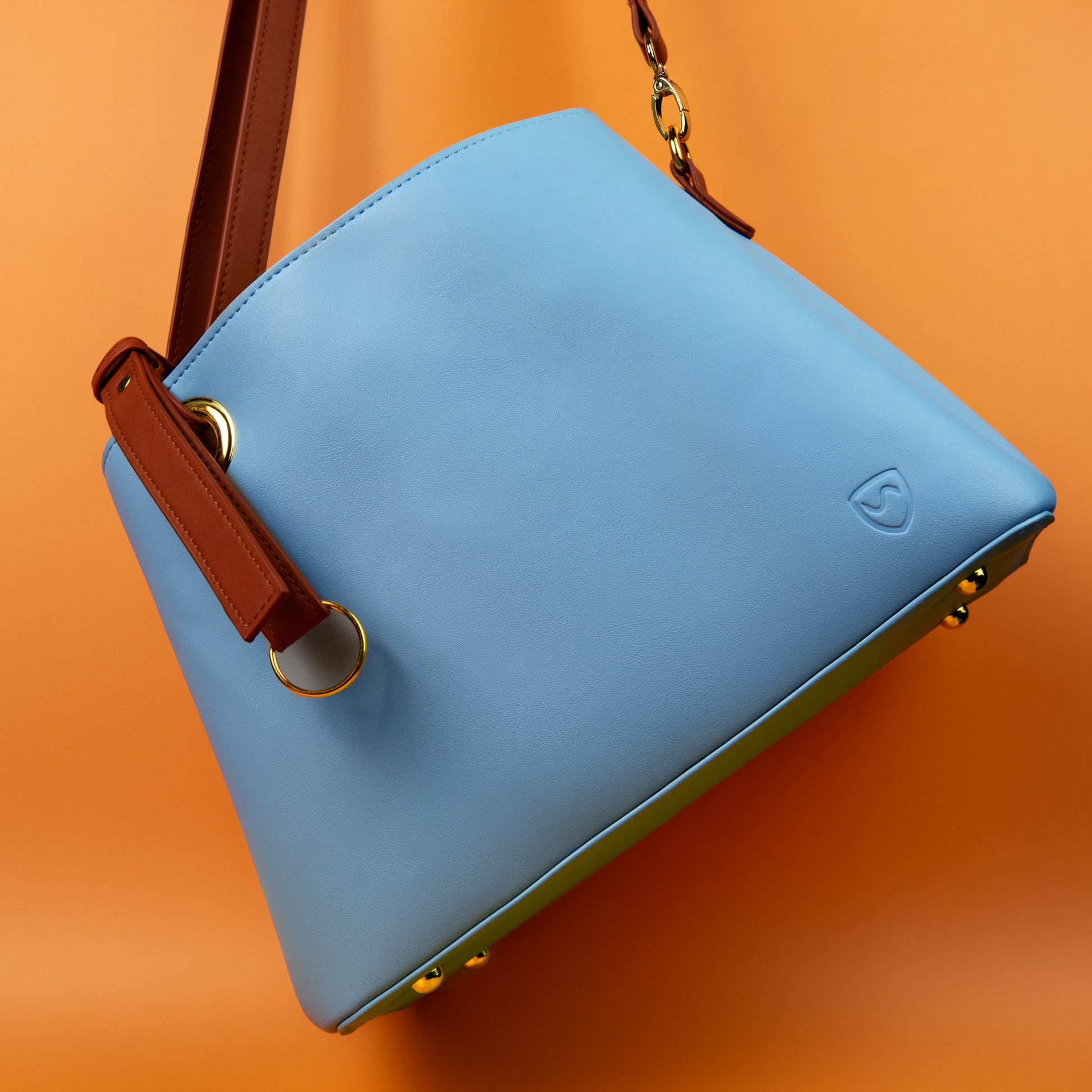 SYB blue shoulder purse with brown strap, embossed logo, and gold hardware
