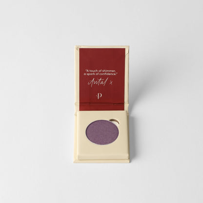 Pressed eyeshadow compact in open box showing a mauve-purple round pan