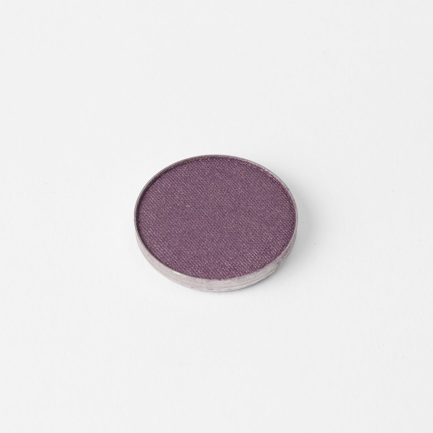 Pressed eyeshadow pan with a mauve-purple shimmer surface in a round case