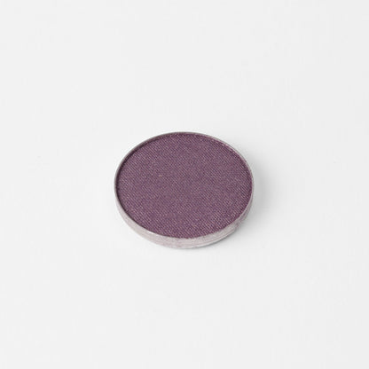 Pressed eyeshadow pan with a mauve-purple shimmer surface in a round case