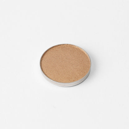 Pressed eyeshadow pan with beige shimmer finish and visible texture