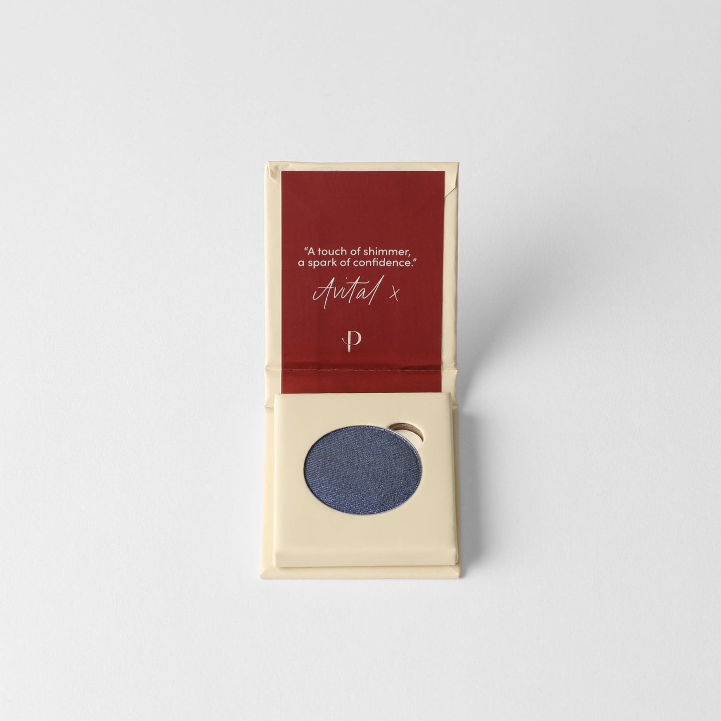 Pressed eyeshadow compact with round pan of dark navy-blue shimmer powder.