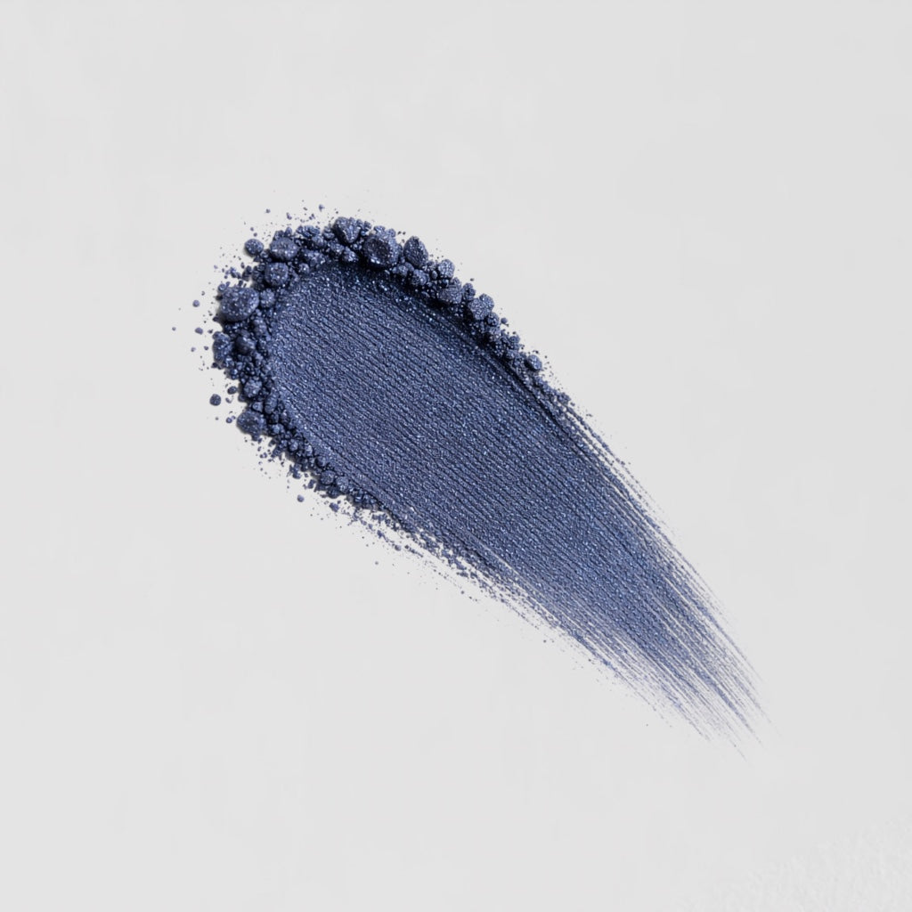 Pressed eyeshadow swatch with dark blue sheen and glittery powder fallout.