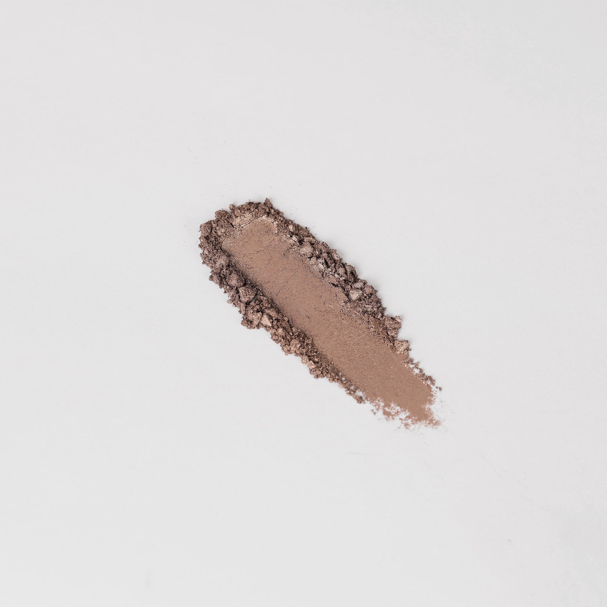 Pressed eyeshadow swatch in muted brown taupe with sparkling, uneven edges