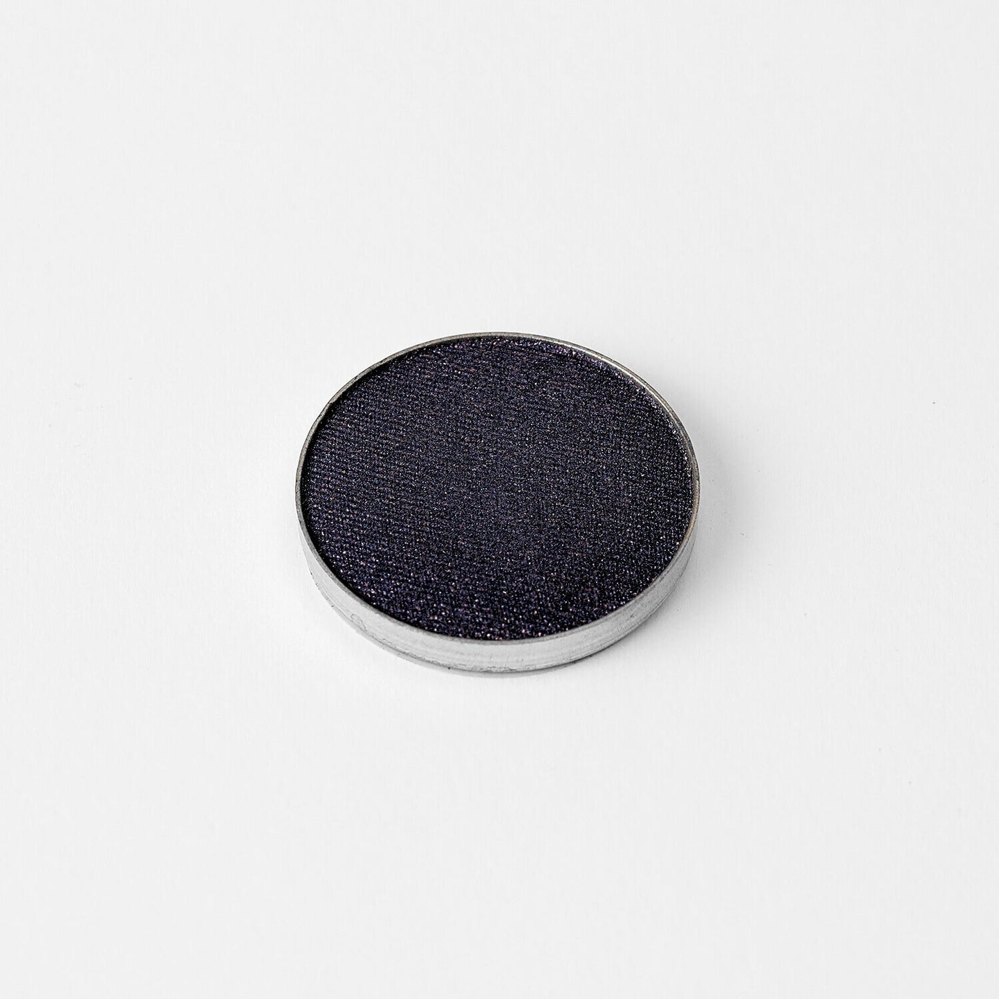 Pressed eyeshadow pan with deep blue-gray shimmer finish and silver rim.