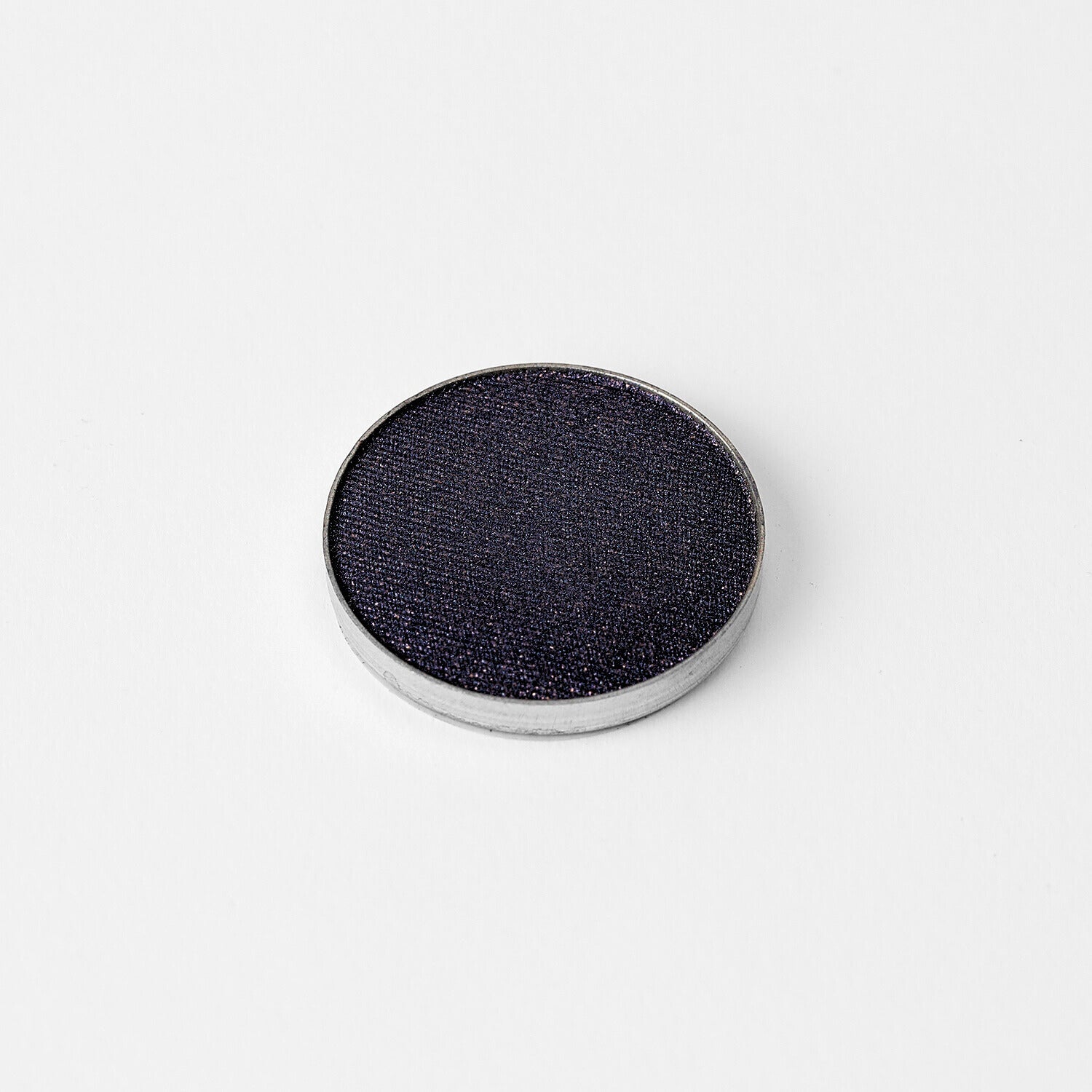 Pressed eyeshadow pan with deep blue-gray shimmer finish and silver rim.