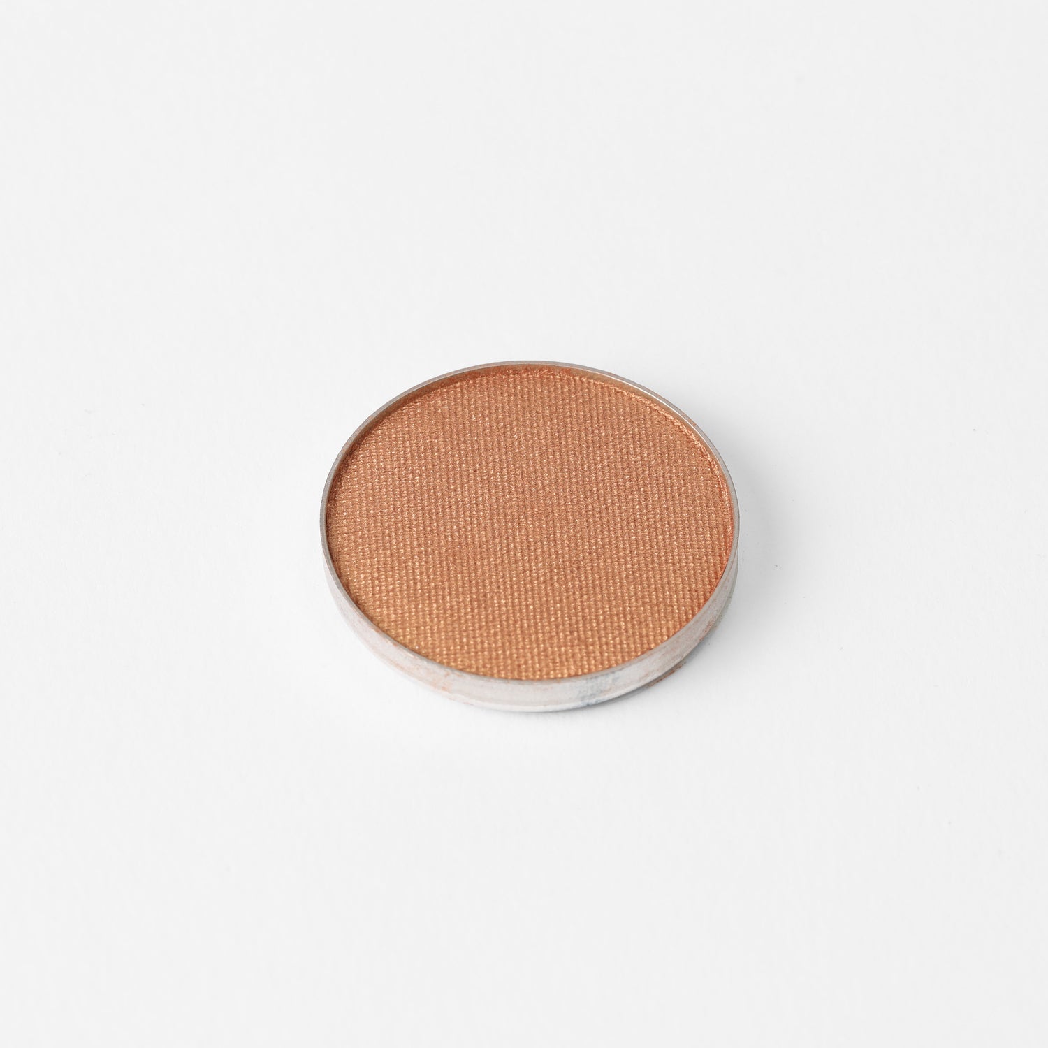 Pressed eyeshadow pan in warm bronze shimmer with smooth circular top