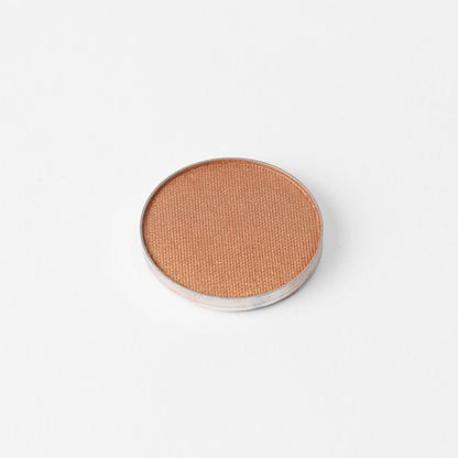 Pressed eyeshadow pan in warm bronze shimmer with smooth circular top