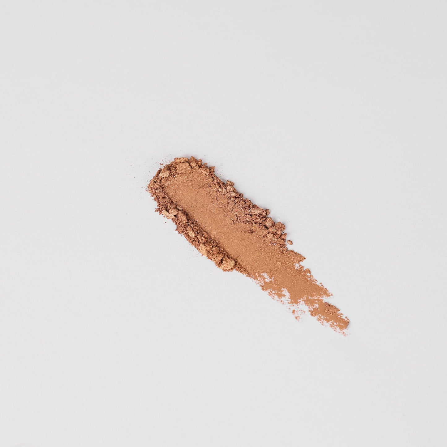 Pressed eyeshadow swatch in medium rose-brown shimmer on skin-like surface