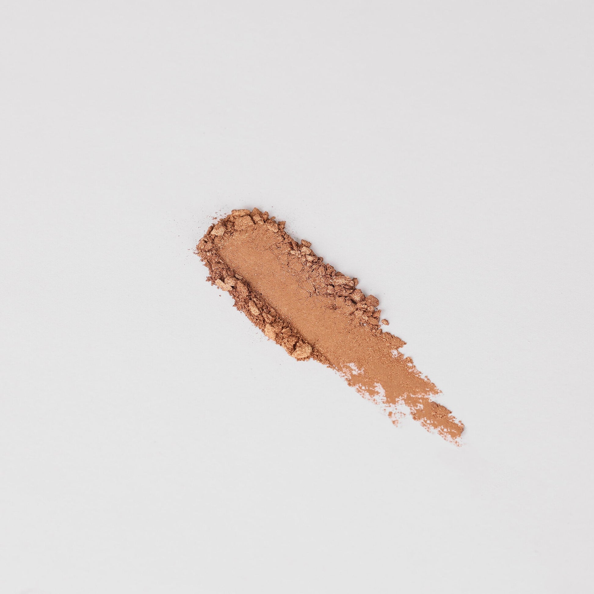Pressed eyeshadow swatch in medium rose-brown shimmer on skin-like surface