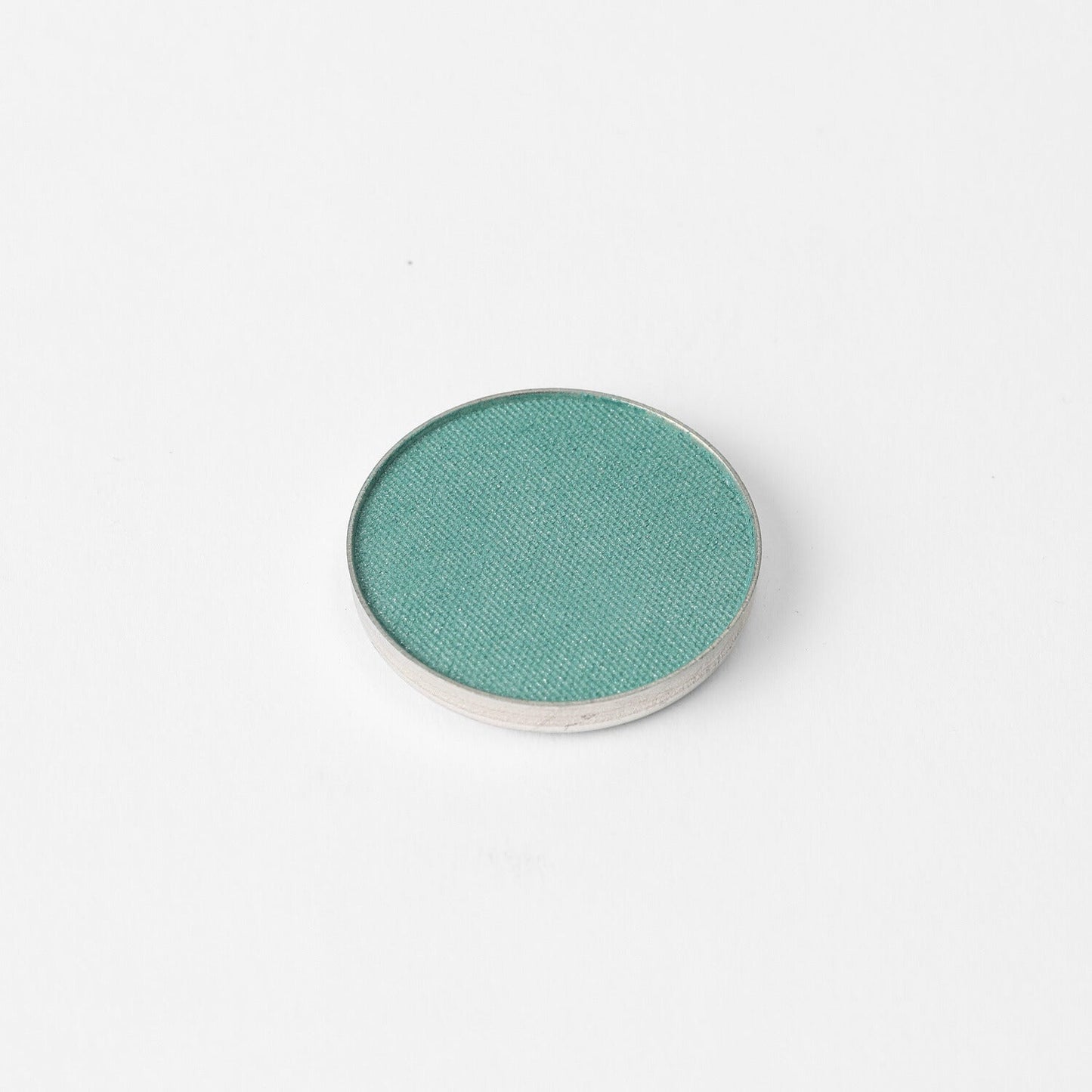 Pressed eyeshadow pan, teal green shimmer in a round compact.