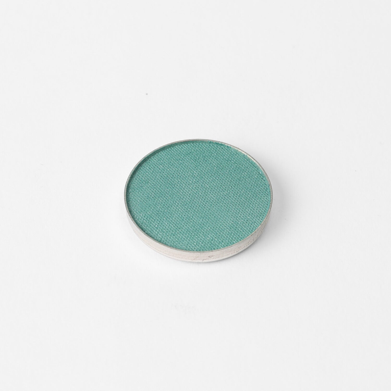 Pressed eyeshadow pan, teal green shimmer in a round compact.