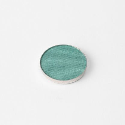 Pressed eyeshadow pan, teal green shimmer in a round compact.