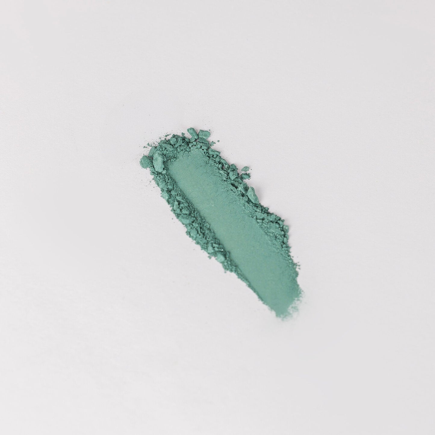 Pressed eyeshadow swatch, teal green shimmer with glittery texture.