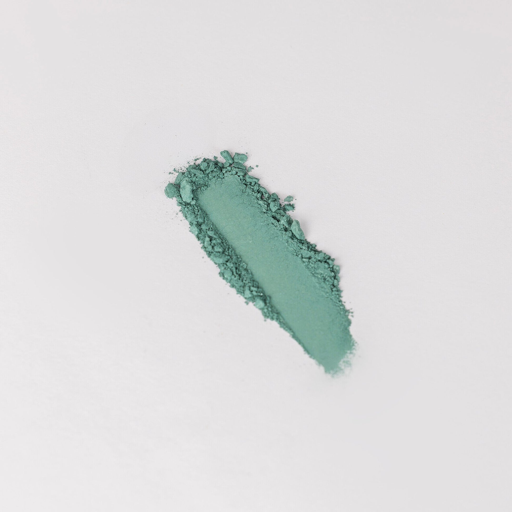 Pressed eyeshadow swatch, teal green shimmer with glittery texture.