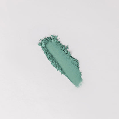 Pressed eyeshadow swatch, teal green shimmer with glittery texture.