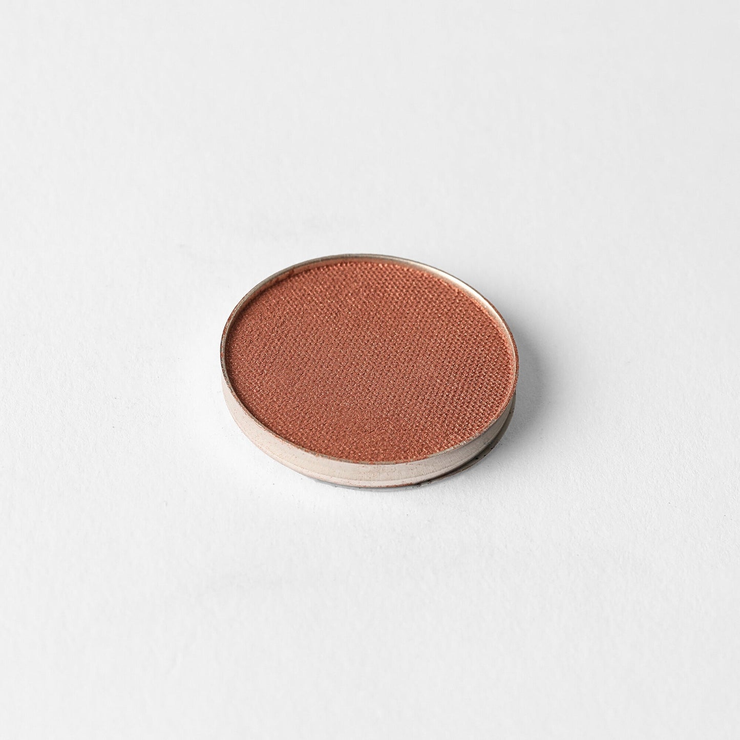 Pressed eyeshadow pan with warm rose-brown shimmer finish in a round compact