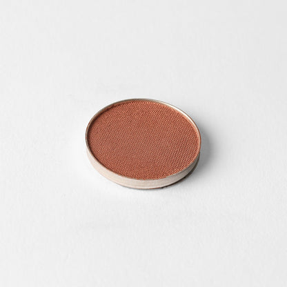 Pressed eyeshadow pan with warm rose-brown shimmer finish in a round compact