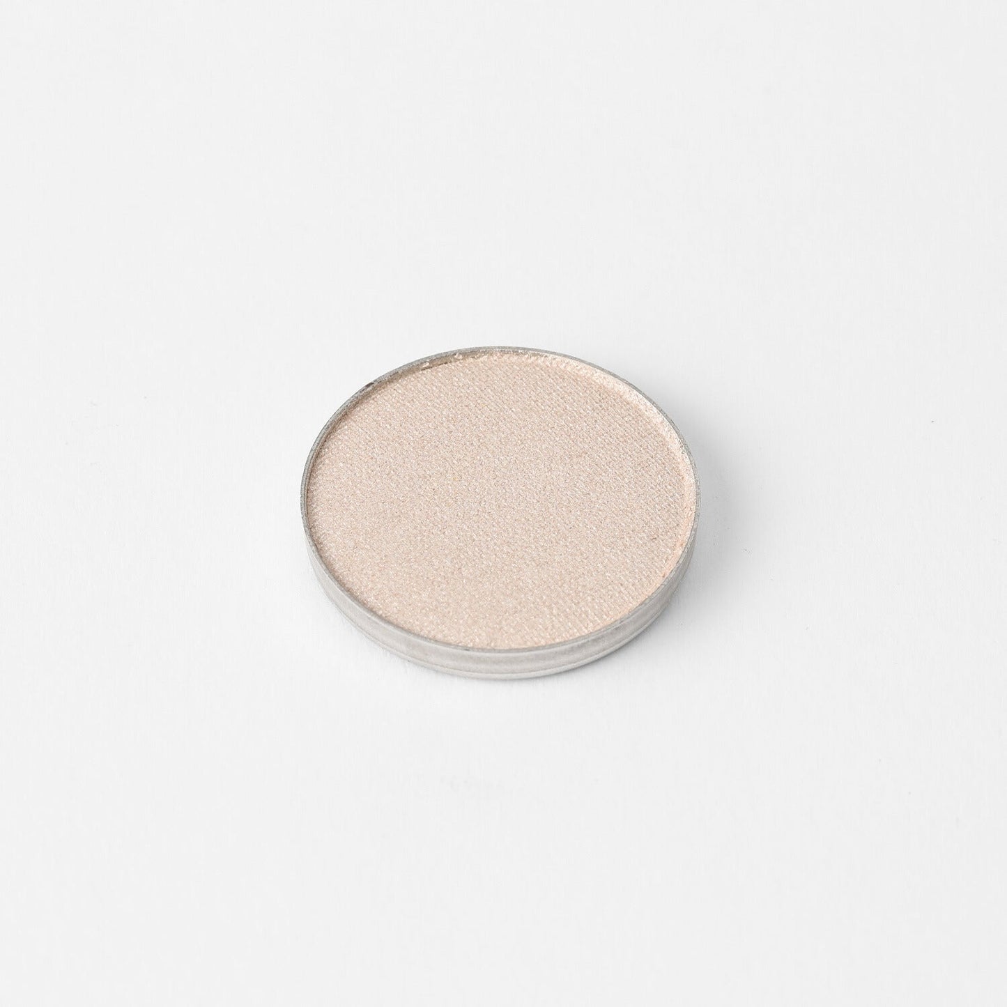 Round pressed eyeshadow pan with pale shimmering neutral finish