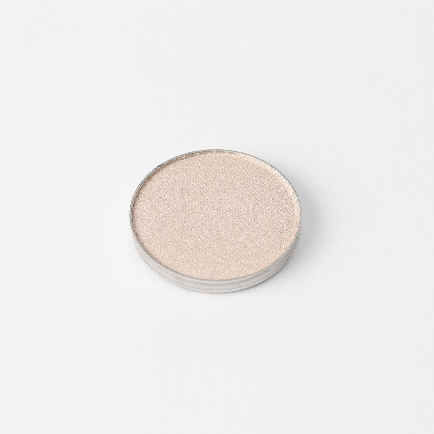 Round pressed eyeshadow pan with pale shimmering neutral finish