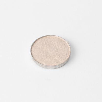 Round pressed eyeshadow pan with pale shimmering neutral finish