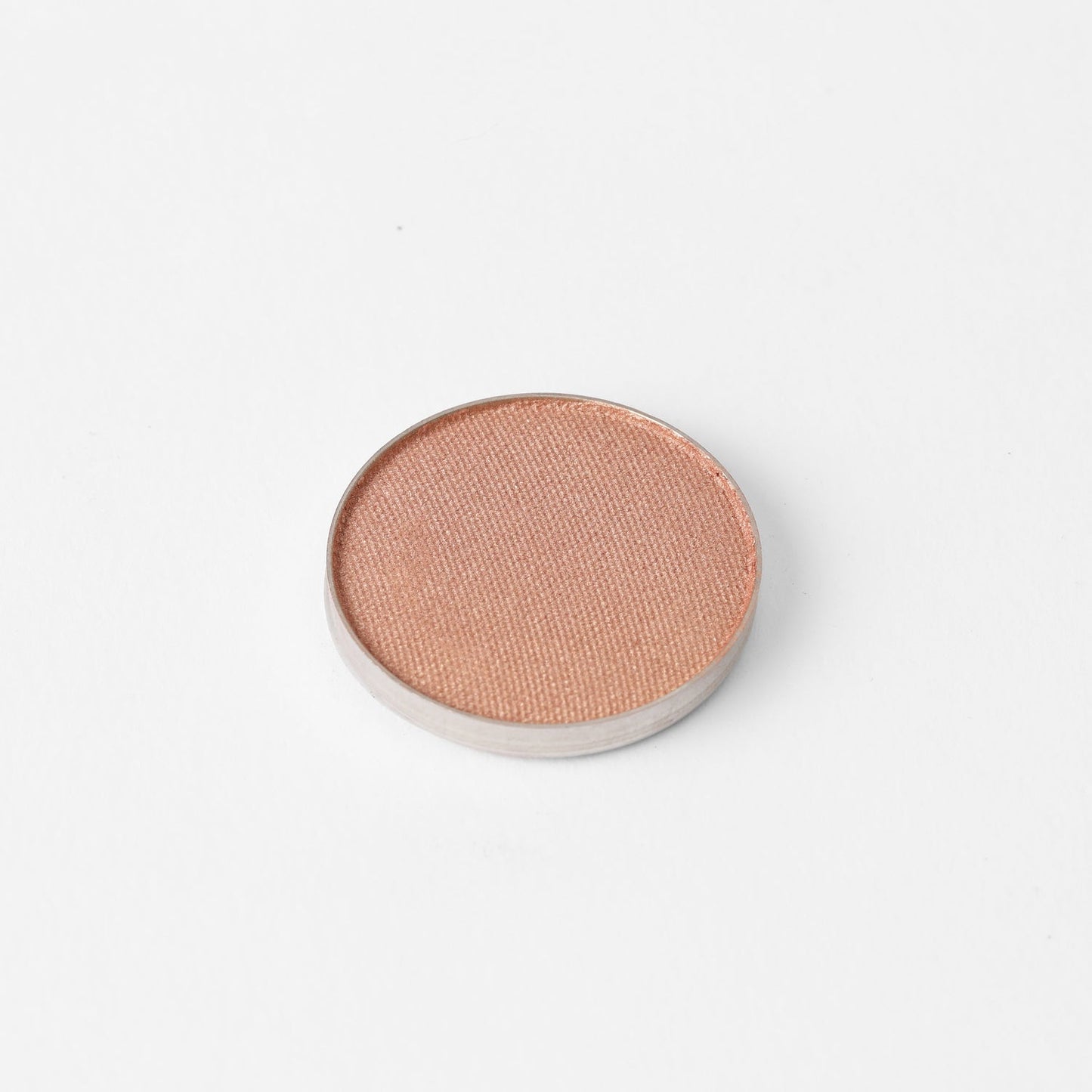 Round pressed eyeshadow pan with warm peach shimmer finish