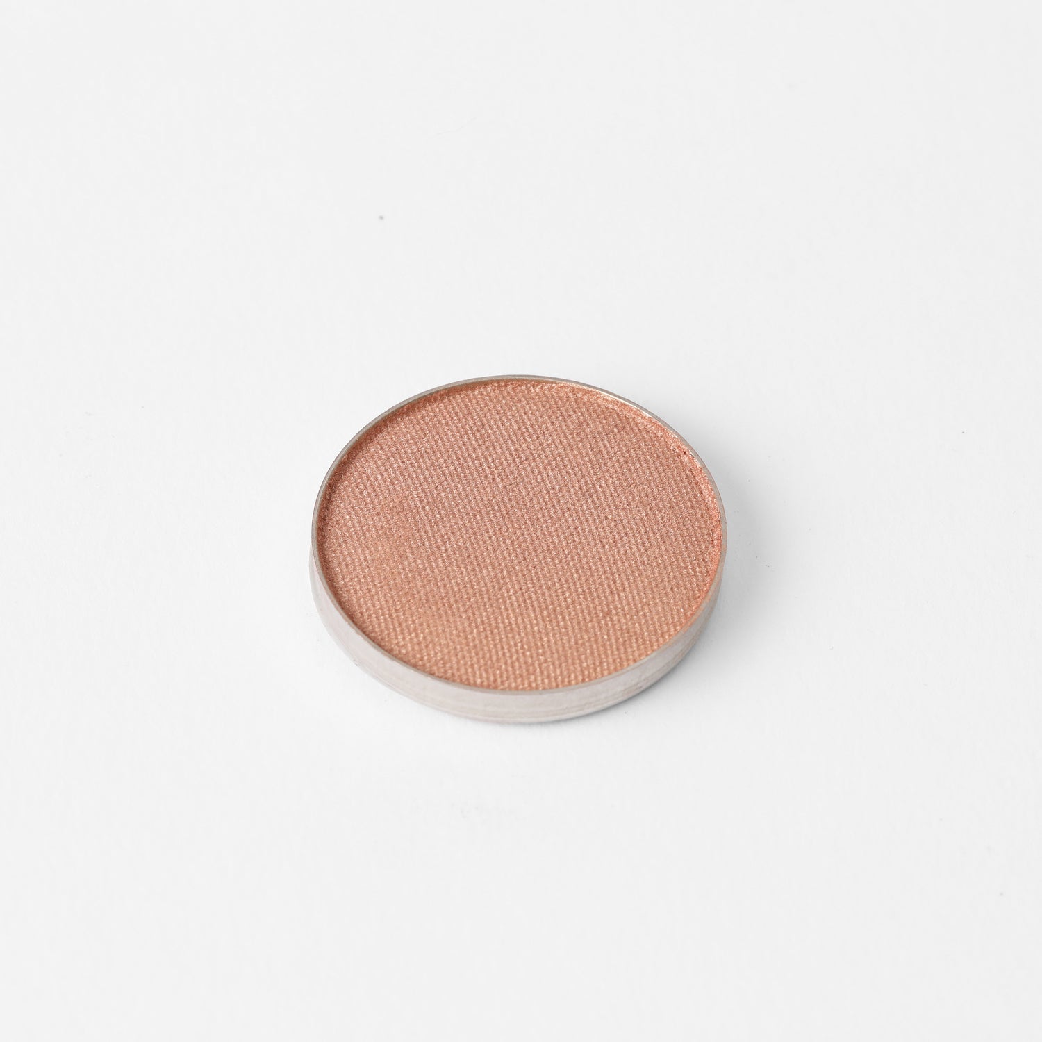 Round pressed eyeshadow pan with warm peach shimmer finish