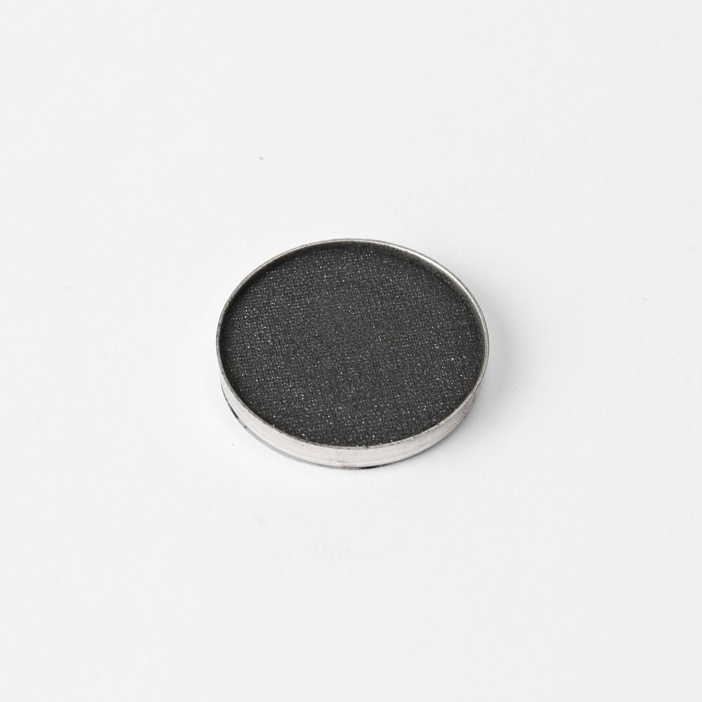 Round pressed eyeshadow pan with dark charcoal shimmer finish