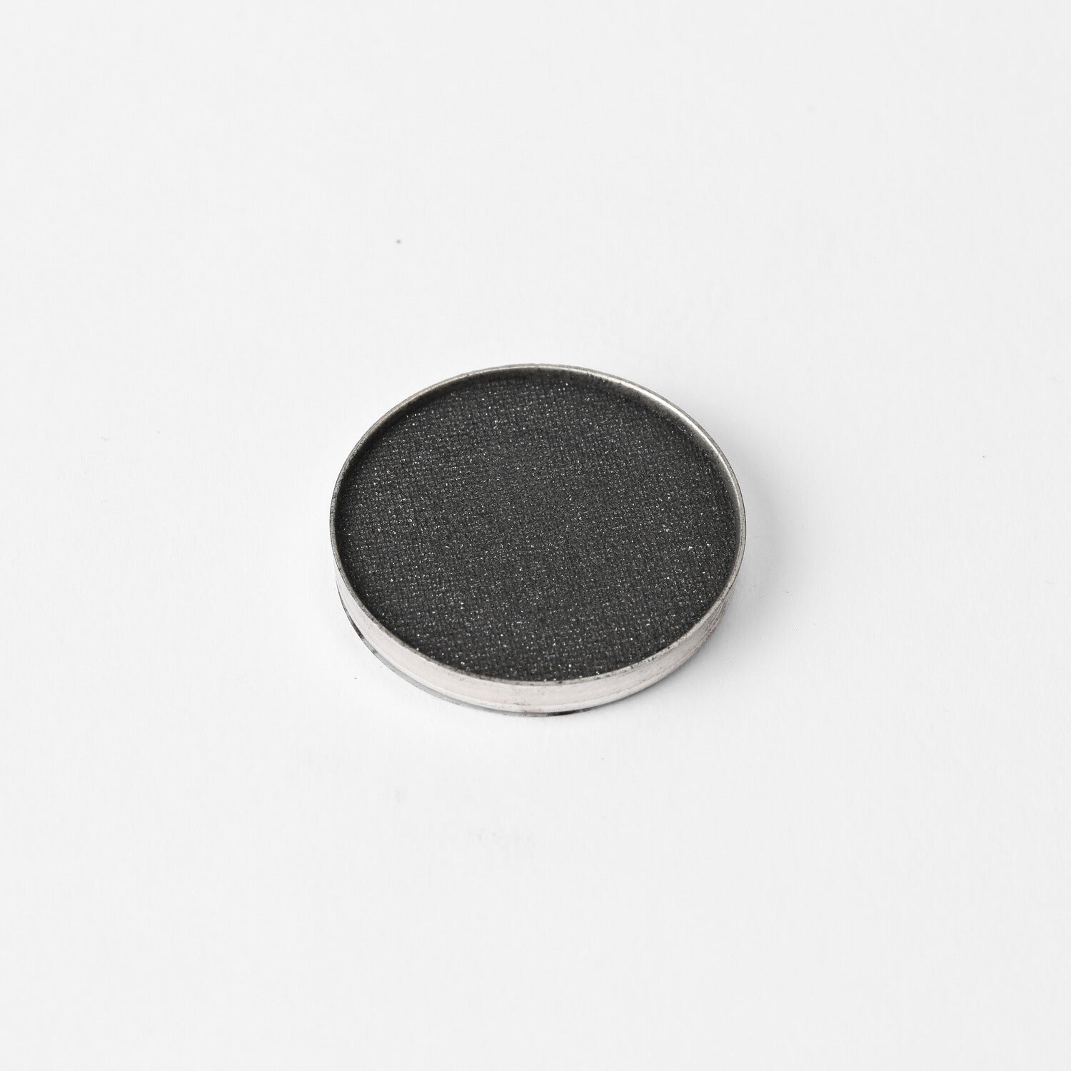 Round pressed eyeshadow pan with dark charcoal shimmer finish