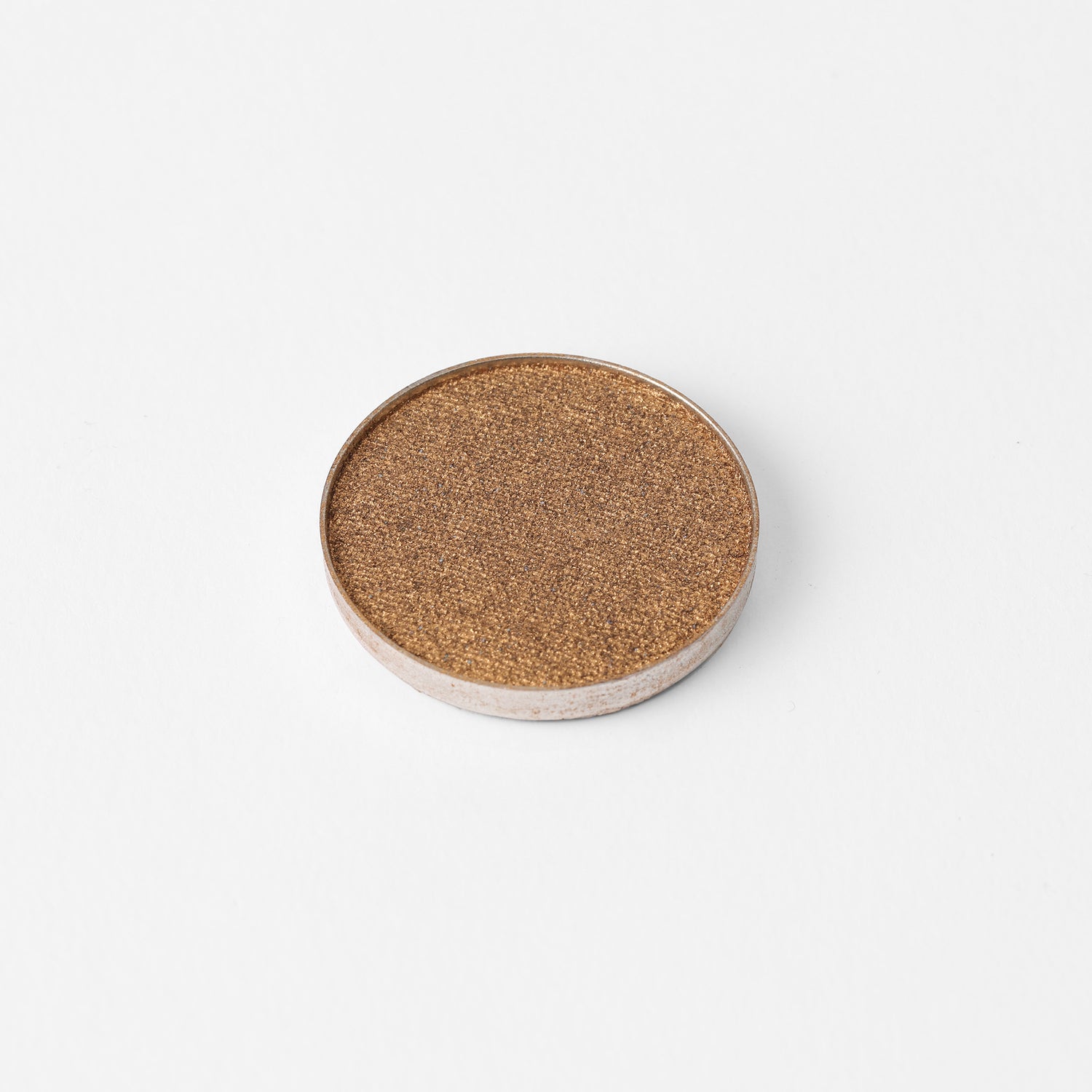 Pressed eyeshadow pan in golden brown shimmer with fine sparkly texture