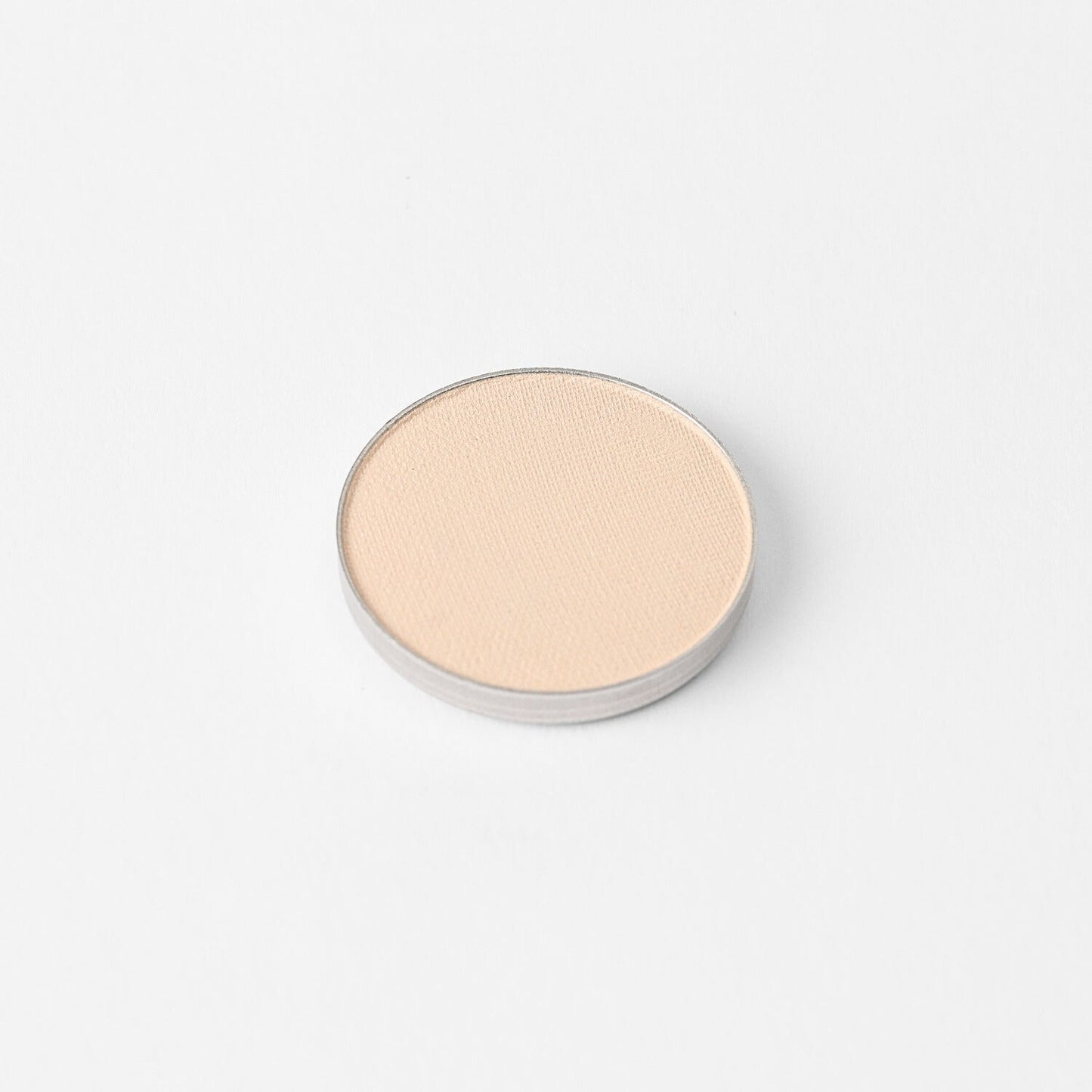 Round pressed eyeshadow pan in a light peachy-pink shimmer tone
