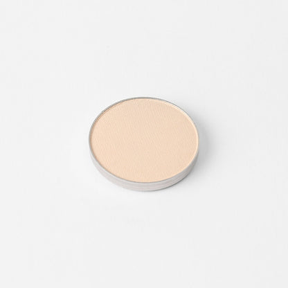 Round pressed eyeshadow pan in a light peachy-pink shimmer tone