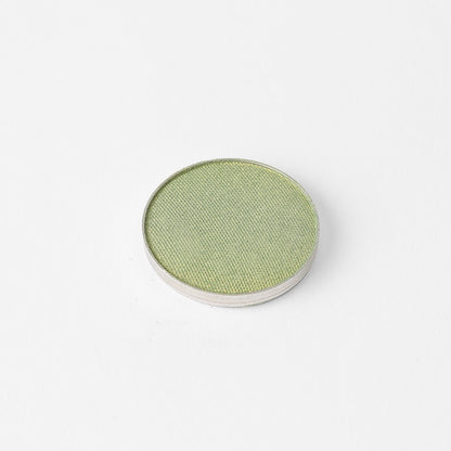 Pressed eyeshadow pan with muted green shade in a round compact.
