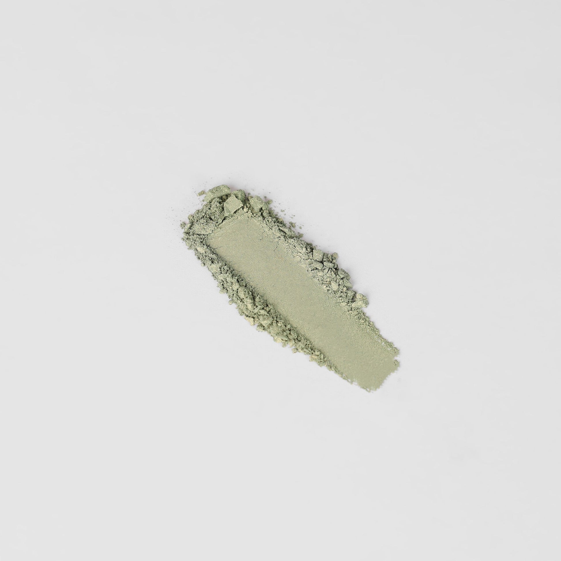 Pressed eyeshadow swatch in cool sage green with crumbly powder texture.