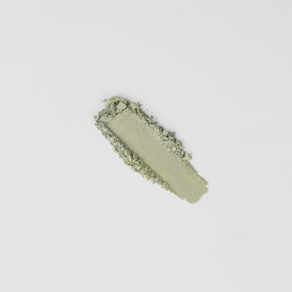 Pressed eyeshadow swatch in cool sage green with crumbly powder texture.