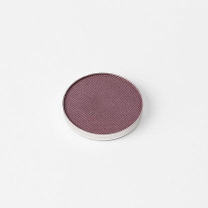 Pressed eyeshadow pan with a smooth purple-mauve shimmer finish in a round case